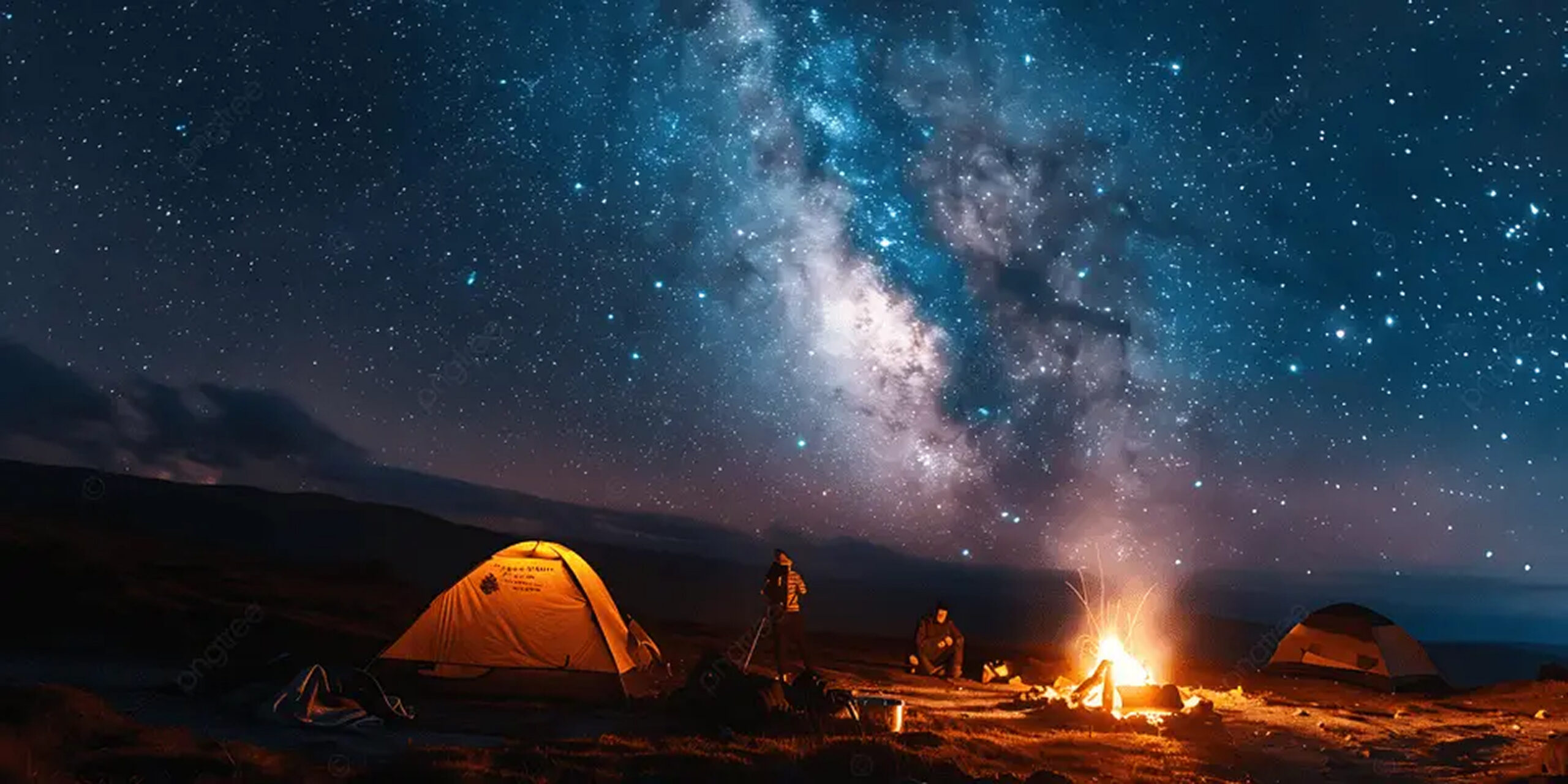 A campsite under a starry sky with a visible Milky Way, featuring tents and a campfire with two people nearby.